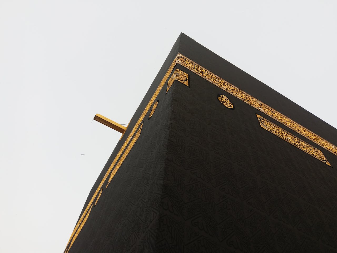 Close-up view of the Kaaba in Mecca, showcasing its intricate gold details against a clear sky.